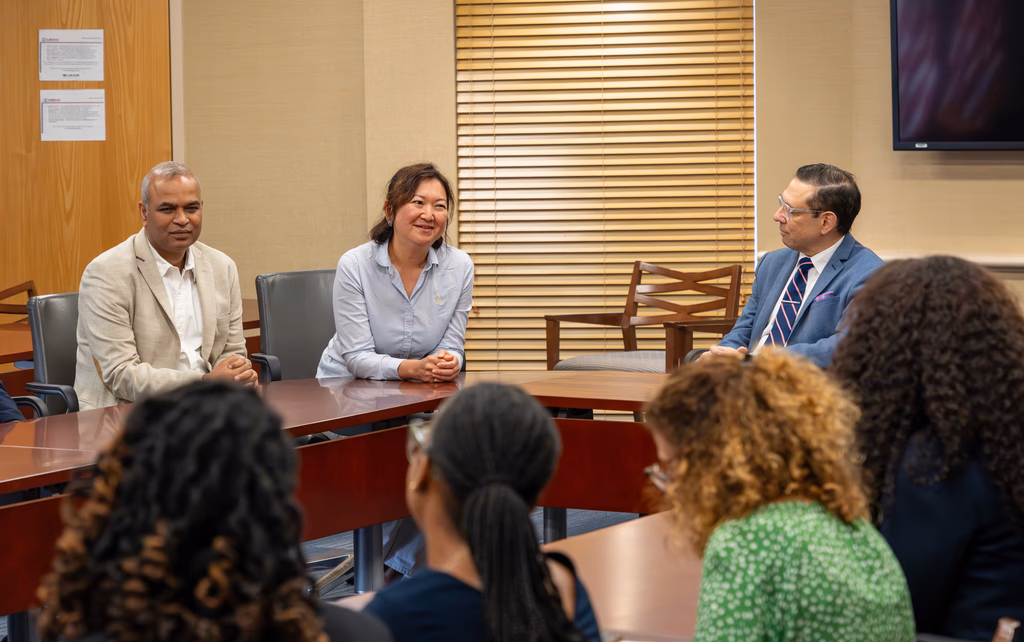 Three executives in conversation across a boardroom table